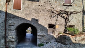 Un arc en pierre mène à une ruelle étroite, bordée d’un chemin pavé et sur laquelle on peut voir un panneau portant le numéro « 15 ».