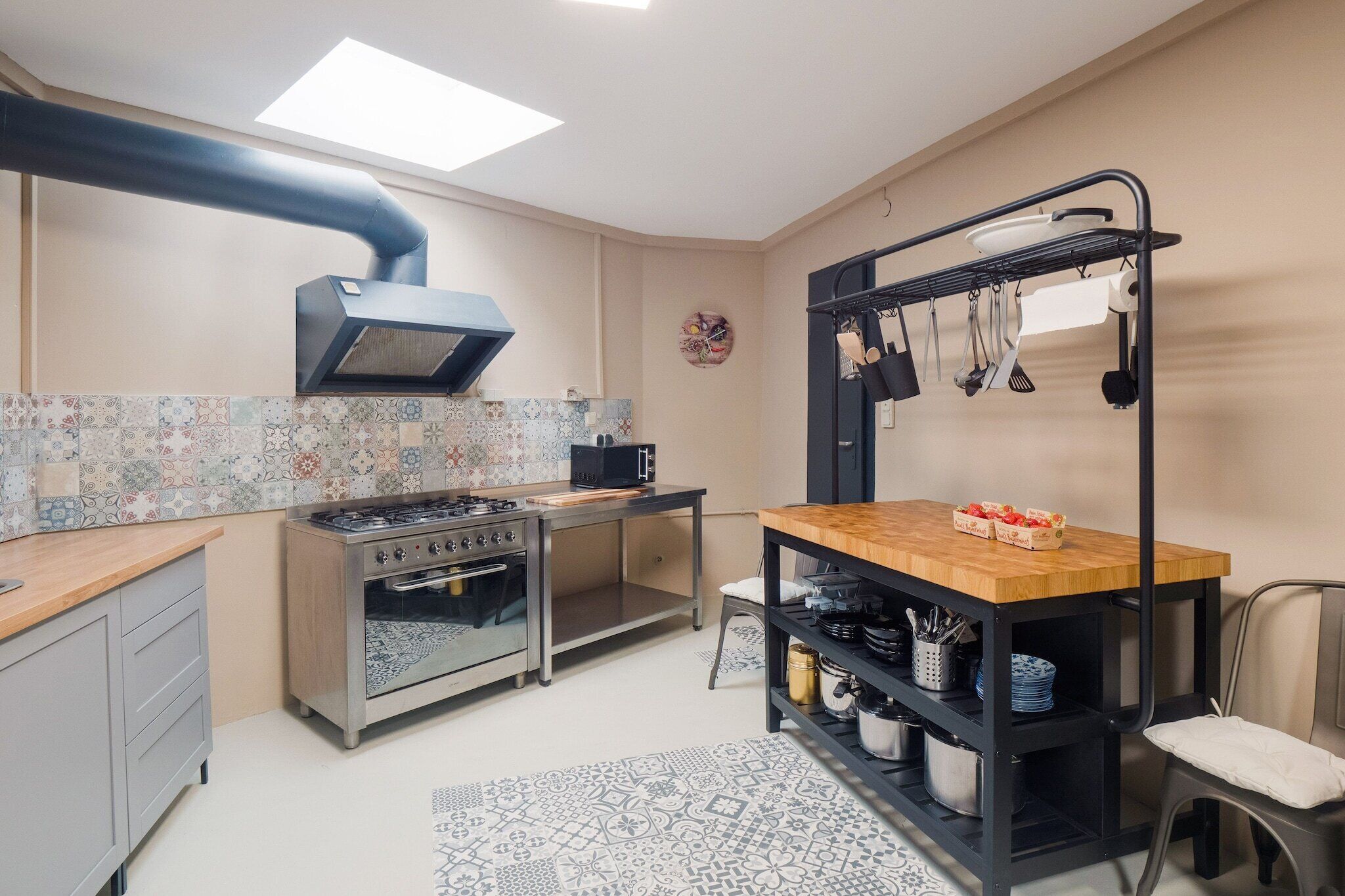 A compact kitchen with a gas stove, oven, and a black hanging rack with utensils.