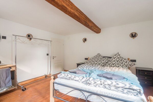 Une chambre à coucher avec un lit, une poutre en bois au plafond, une armoire et une table de chevet.