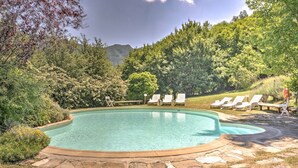 Ein Schwimmbecken mit Liegestühlen und einem Kiesweg.