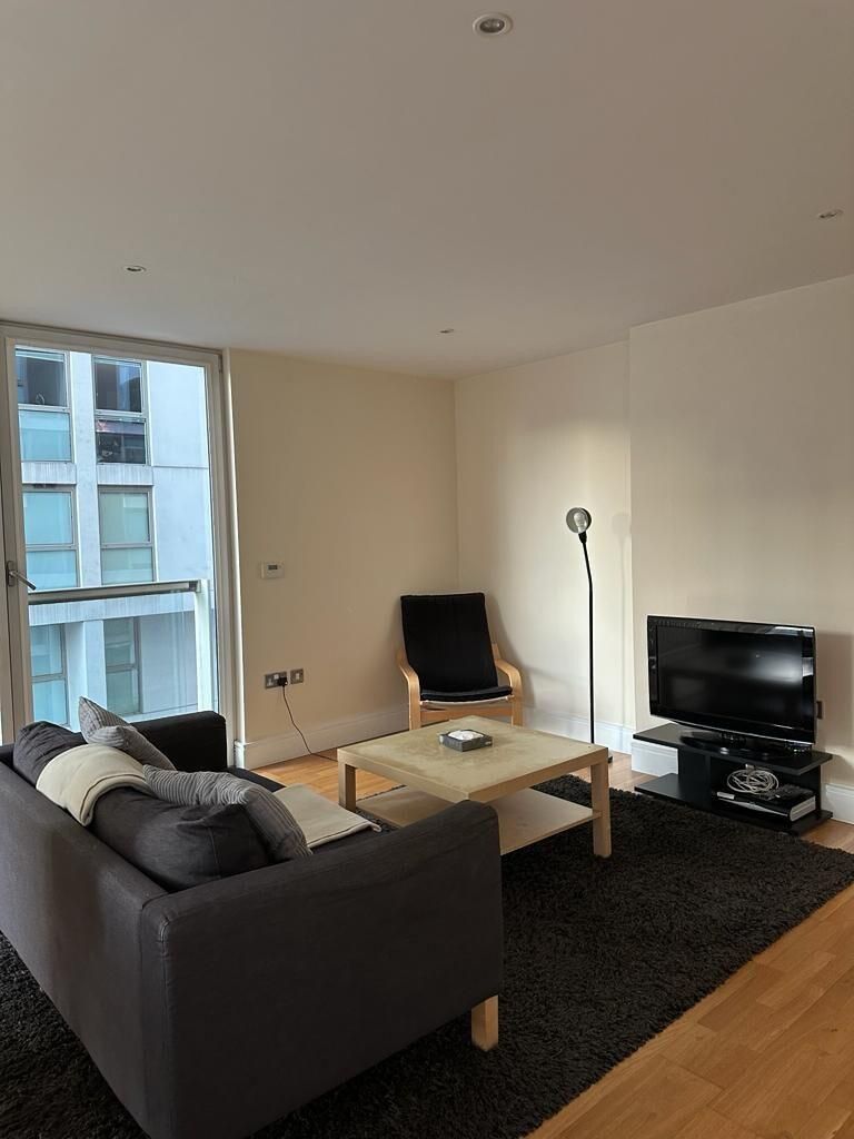 Un salon moderne avec un canapé, une table basse, un téléviseur et un fauteuil.