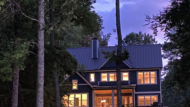 Una casa moderna de dos pisos con amplios ventanales, una escalera visible y un exterior bien iluminado.
