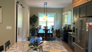 Una cocina con encimera de mármol, refrigerador y zona de comedor con mesa y sillas.