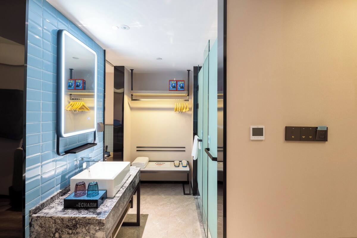 Un baño moderno con encimera de mármol, un espejo grande, un perchero y un calentador empotrado.