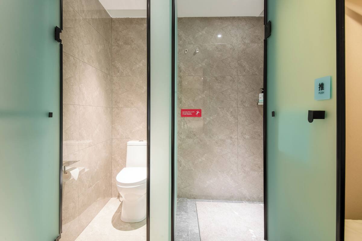 Un baño moderno con inodoro, un botón pulsador y un letrero de seguridad.