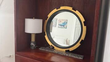 A wooden wardrobe with a mirror, a lamp, and a small shelf.