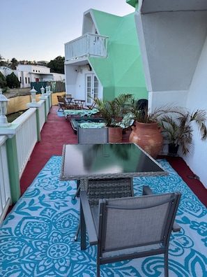 Una terraza en la azotea con asientos exteriores, plantas en macetas y vistas del entorno.