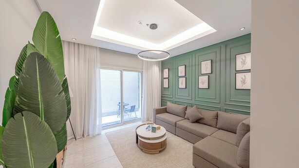 A modern living room with a sofa, a coffee table, and large green plants. - Mabaat - Al Narjis - 549 (Riyadh)
