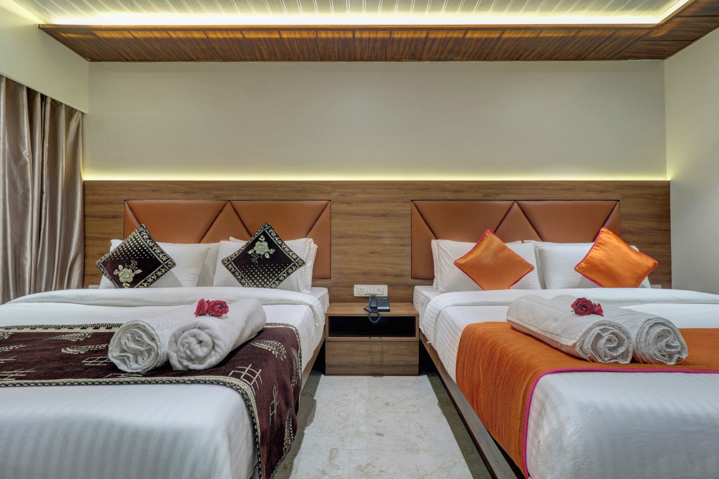 A hotel room with two beds, wooden headboards, and a nightstand between them.