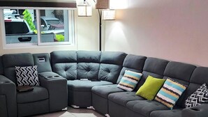 En moderne stue med en hjørnesofa, et lille bord og en gulvlampe.