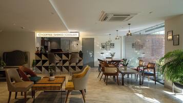 A modern interior with a coffee bar, seating area, and large windows.