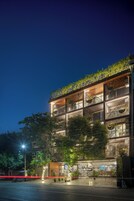 A multi-story building with balconies, outdoor seating, and a well-lit entrance.