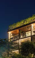 A multi-story building with balconies, large windows, and a rooftop garden.