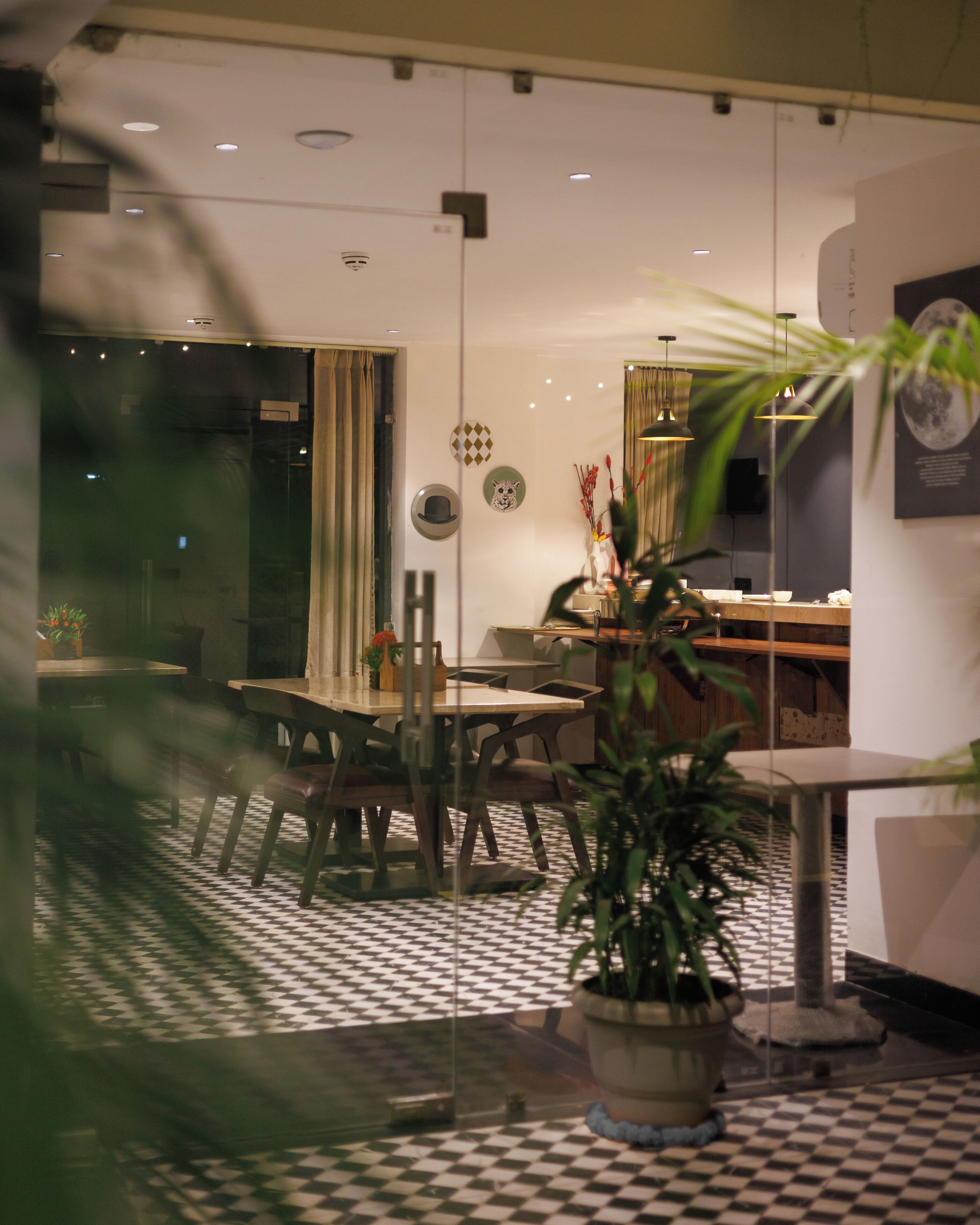 A dining area with a checkered floor, a table with chairs, and a potted plant.