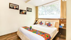 A hotel room with a large bed, a window with curtains, and three framed pictures on the wall. - New Axis By Glitz Hotels (Mumbai)