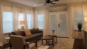 A living room with a sofa, coffee table, and a ceiling fan. - Cozy Retreat in Greater Heights (Houston)