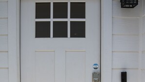 A white door with a keypad lock, a peephole, and a doorbell. - Cozy Retreat in Greater Heights (Houston)