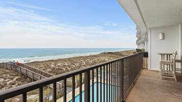 A balcony with a view of the beach and ocean.