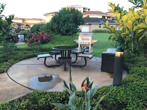 Une terrasse avec un barbecue, une table de pique-nique et des sièges d’extérieur.