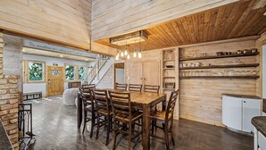 Interior de madera con una mesa de comedor, sillas, una escalera y una zona de cocina.