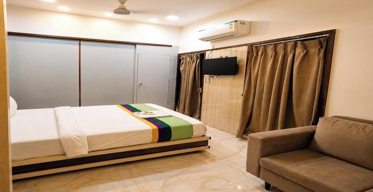 A hotel room with a bed, a sofa, a TV, and a wardrobe.
