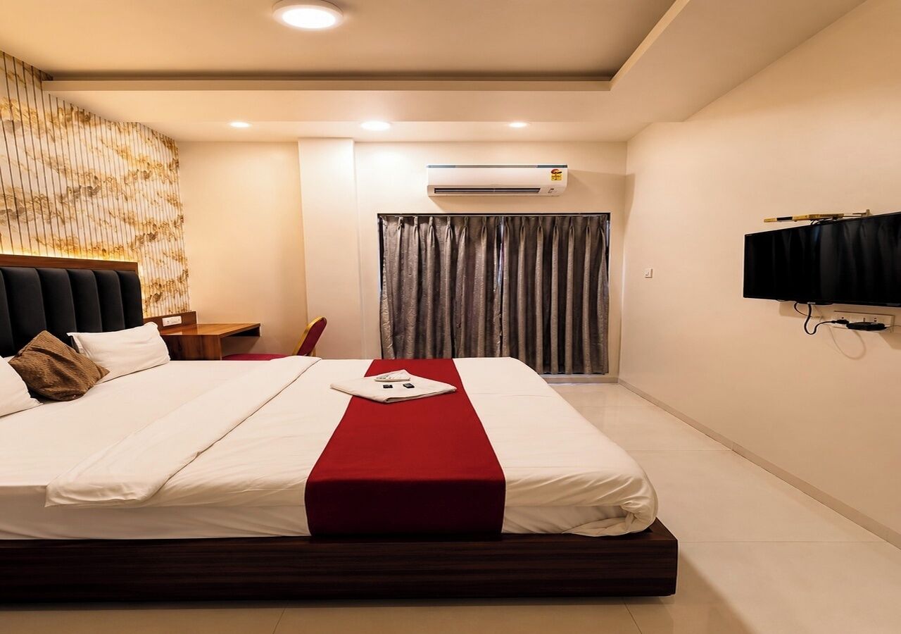 Habitación de hotel con una cama grande, televisión de pantalla plana, equipo de aire acondicionado y cortina.