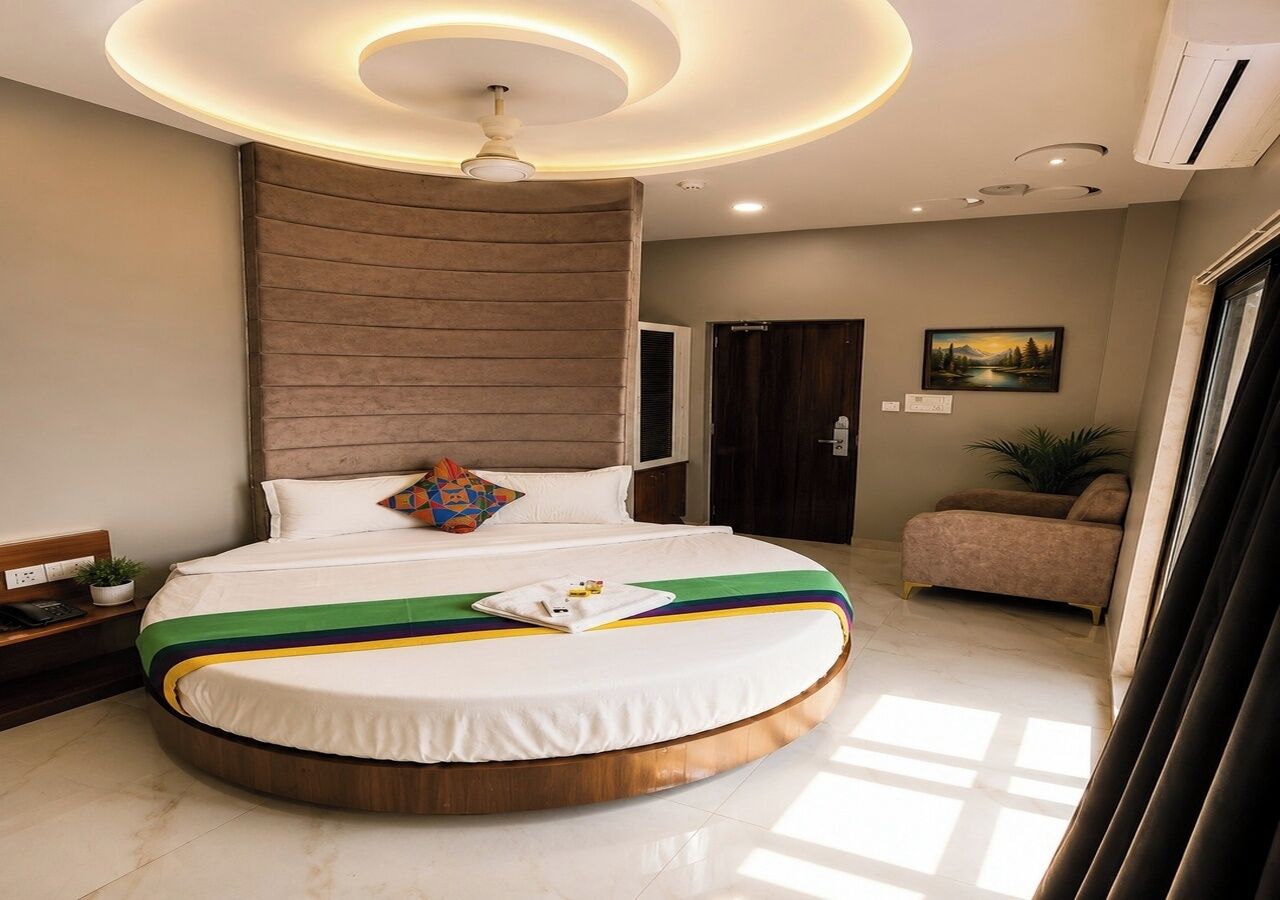 A circular bed with a white and green striped bedspread, a ceiling light fixture, and a brown headboard.