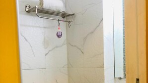 A bathroom with a white marble wall, a black countertop, a white sink, and a towel rack with a towel and a purple soap dispenser. - New Seven Hills By Glitz Hotels (Mumbai)