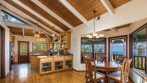 Uma cozinha ampla com armários de madeira, uma ilha central e uma área de jantar com uma mesa grande e cadeiras.