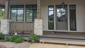 Ein modernes, zweistöckiges Haus mit Steinfundament, großen Fenstern und einer Veranda.