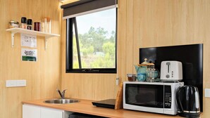 Une cuisine compacte équipée d’un évier, d’un four à micro-ondes, d’un grille-pain et d’une machine à café, le tout installé sur le plan de travail.