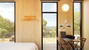 Une chambre à coucher avec un lit, un bureau avec un ordinateur portable et une vue sur l’extérieur.