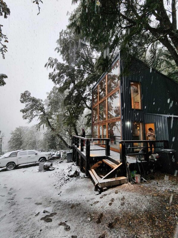 A cabin with a glass front, wooden deck, and a small porch.