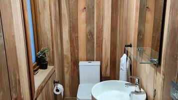 A wooden-paneled bathroom with a toilet, sink, and mirror.