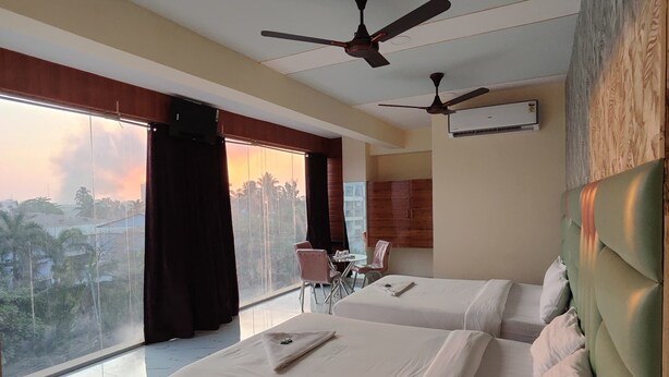 Una habitación de hotel con dos camas, un comedor y vistas a palmeras.