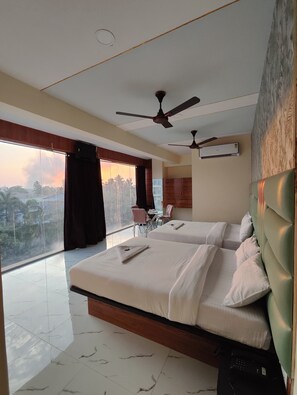 A hotel room with two beds, a dining area, and a view of palm trees. - Balaji Residency By Glitz Hotels (Kalyan)