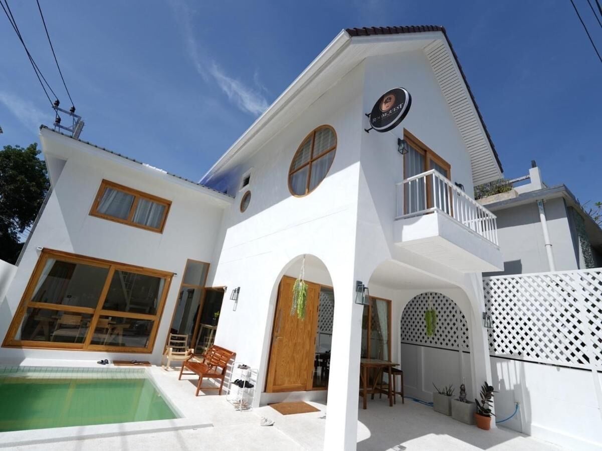 A two-story white house with a balcony, a swimming pool, and a patio area.