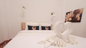 A hotel room with a neatly made bed, two bedside lamps, and a floral painting on the wall. - RIM HuaHin Villa By RoomQuest (Hua Hin)