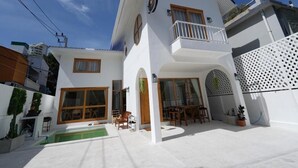 A two-story house with a balcony, a swimming pool, and a patio area with outdoor furniture. - RIM HuaHin Villa By RoomQuest (Hua Hin)