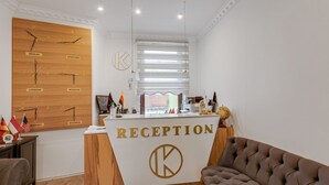Un mostrador de recepción con un panel de madera que muestra nombres de ciudades y un gran logotipo 'K'.