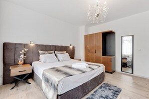 A modern bedroom with a large bed, wooden wardrobe, bedside table, and a chandelier. - Apartment in Oberhausen near Scenic Lake (Oberhausen)