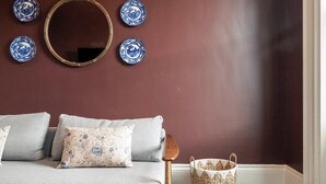 Una stanza con un divano, uno specchio e piatti decorativi appesi al muro.