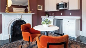 Cucina con mobili bianchi, piano cottura nero, forno a microonde e una sedia arancione.