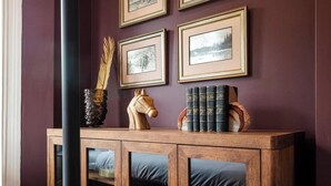 Un mobile in legno con ante in vetro, un vaso con piume e libri sopra.