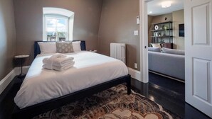 A bedroom with a bed, a radiator, a window, and a view of a bathroom. - The Chester: Modern, Cool, Heart Of South End (Boston)