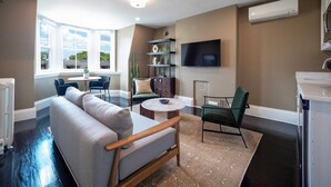 A modern living room with a sofa, chairs, a TV, and a fireplace. - The Chester: Modern, Cool, Heart Of South End (Boston)