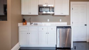 A kitchen with white cabinets, a stainless steel microwave, and a dishwasher. - The Chester: Modern, Cool, Heart Of South End (Boston)