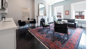 A modern living room with a fireplace, a dining area with a table and chairs, a sofa, and a large window with a view. - The Chester: Modern Luxury, Historic Charm (Boston)