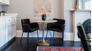 A dining area with a round table, two chairs, a potted plant, and a framed cityscape poster on the wall. - The Chester: Modern Luxury, Historic Charm (Boston)