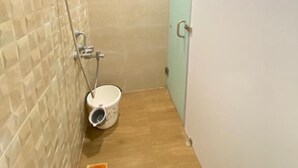 Een kleine badkamer betegeld met een douche, toilet en wastafel.